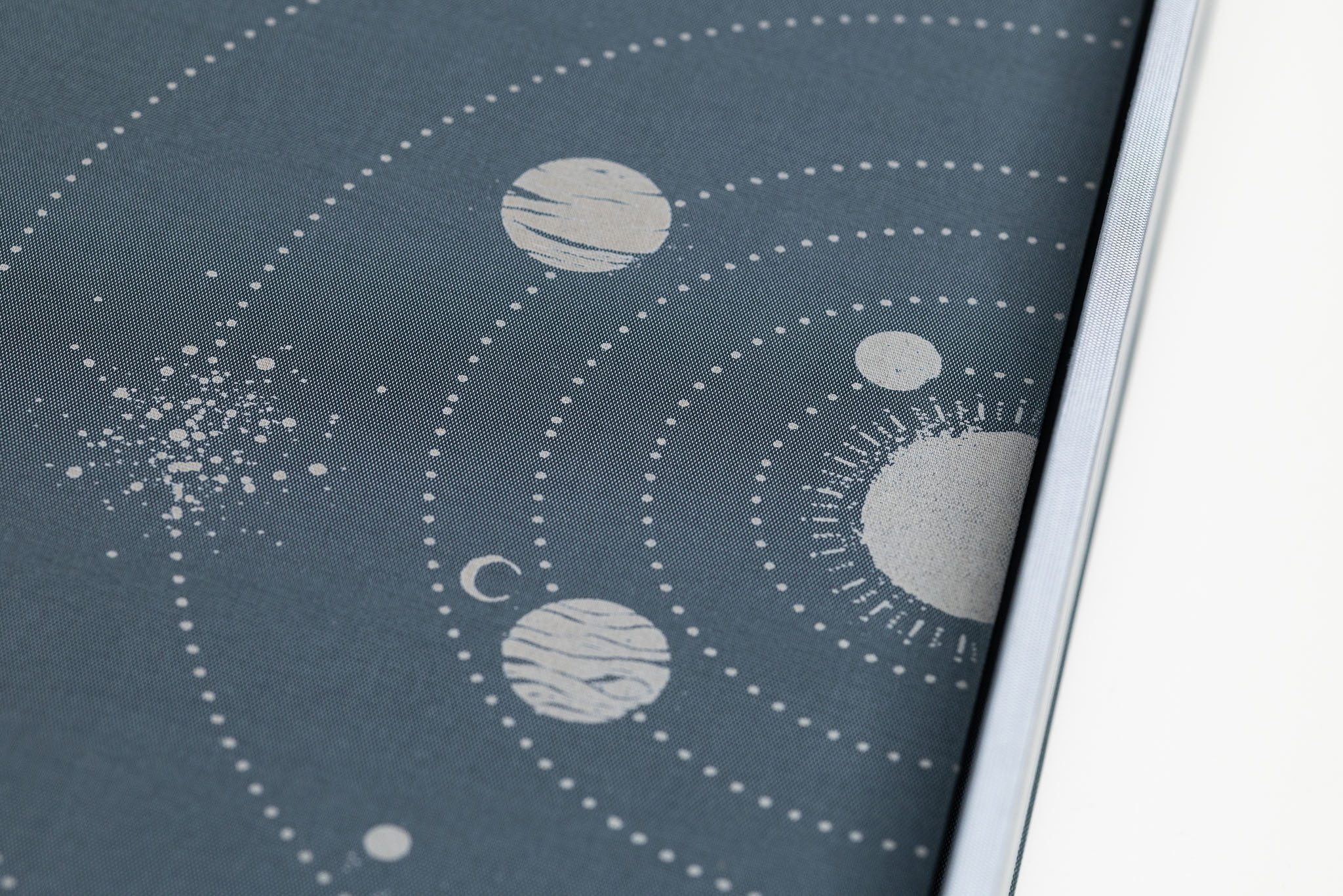 Dettaglio ravvicinato dell'incisione laser a tema astronomico personalizzata sulla copertina in seta topazio dell'album Inciso.